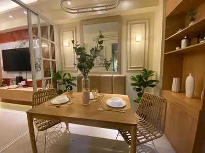 a dining table and chairs in a living room at Hallin Bay Suites Modern 1BR with balcony in Manila