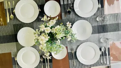 a table with white plates and a vase of flowers at 2 bedroom Luxury Condo in Eastwood with Scenic City view, unli wifi and netflix in Manila