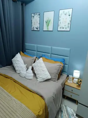 a blue bedroom with a bed with towels on it at SkyShore Suites in Manila