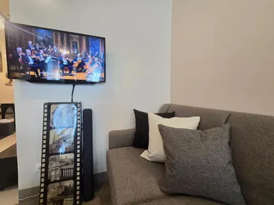a living room with a couch and a tv on the wall at Very Cosy One Uptown near Grand Hyatt Hotel BGC Uptown Mall and St Lukes Medical Center in Manila