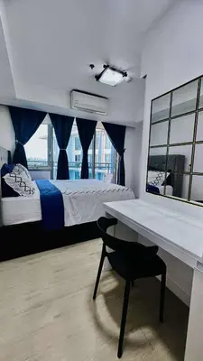 a bedroom with a bed and a desk with a chair at L A Azure staycation in Manila