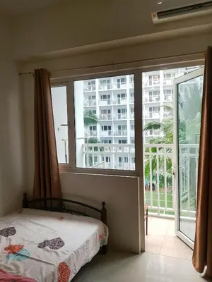 a bedroom with a bed and a large window at Jaina Staycation in Manila