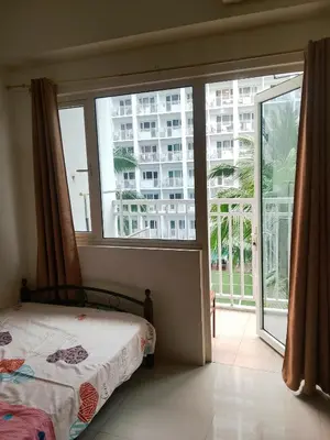 a bedroom with a bed and a large window at Jaina Staycation in Manila