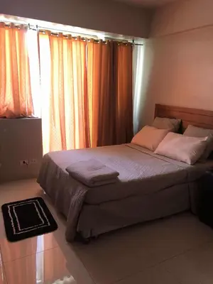 a bedroom with a bed with pink pillows and a window at Sun Property in Manila