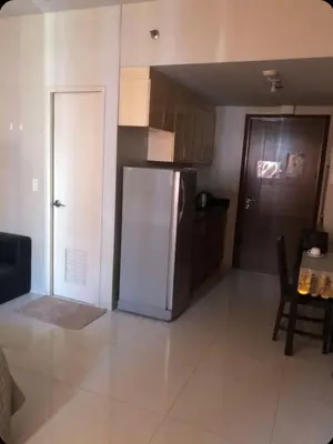 a kitchen with a refrigerator and a table and a door at Sun Property in Manila