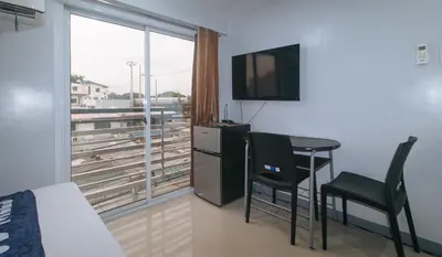 a room with a table and a television and a window at VCloud Hills Boarding House Near NAIA Terminal in Manila