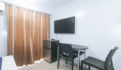 a room with a table and a tv on a wall at VCloud Hills Boarding House Near NAIA Terminal in Manila