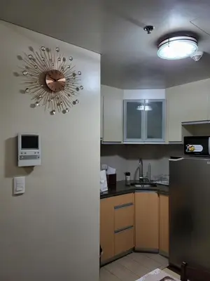 a kitchen with a refrigerator and a clock on the wall at Liana's Condo Newport City in Manila