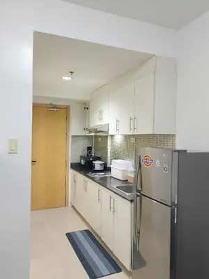 a kitchen with white cabinets and a stainless steel refrigerator at Tower F Sea Residence in Manila