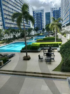 a resort with a pool and chairs and palm trees at Sea Residences Golden Empire in Manila