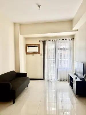 a living room with a couch and a television at Levi & Moon's Manila Bay in Manila