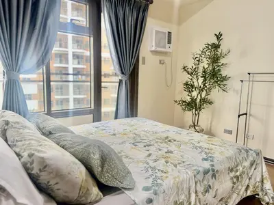 a bedroom with a bed with blue curtains and a window at Levi & Moon's Manila Bay in Manila