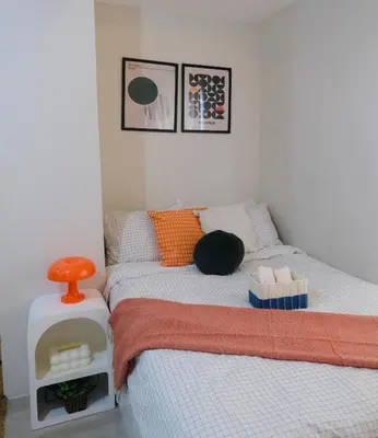 a small bedroom with a bed with an orange stool at Modern Retro Stay near NAIA 3 in Manila