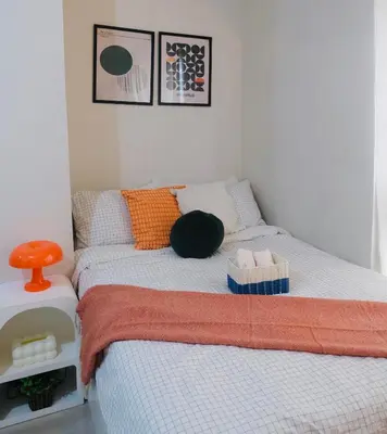 a bedroom with a bed with an orange and blue blanket at Modern Retro Stay near NAIA 3 in Manila