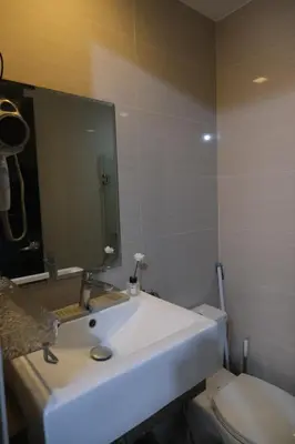 a bathroom with a sink and a toilet and a mirror at Modern Retro Stay near NAIA 3 in Manila