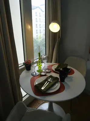 a white table with plates and wine glasses in front of a window at Modern Retro Stay near NAIA 3 in Manila