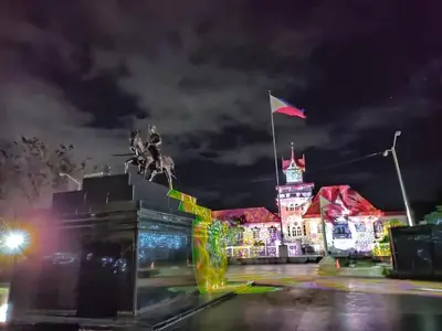 a building with a flag and a statue at night at Auntie's in Tanza
