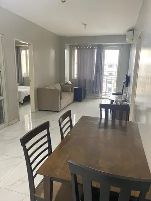 a living room with a table and chairs and a couch at Monarch Park Suites WS in Manila