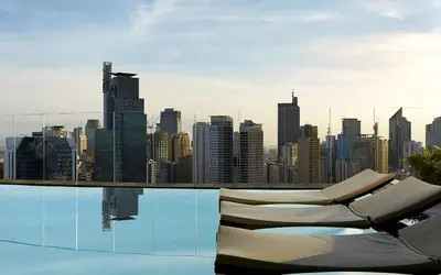 a pool with chairs and a city skyline in the background at E-Studio,Best Sunset Pool,Luxury,Hotel Style in Manila