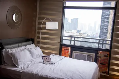 a bed with a laptop on it in front of a window at E-Studio,Best Sunset Pool,Luxury,Hotel Style in Manila
