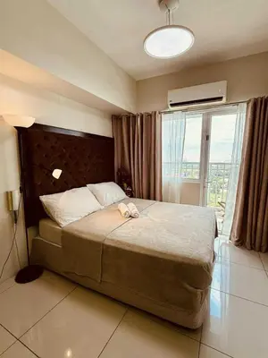 a bedroom with a large bed and a large window at Breeze Staycation by Charmed in Sampong