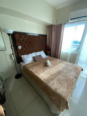 a bedroom with a large bed with a large window at Breeze Staycation by Charmed in Sampong