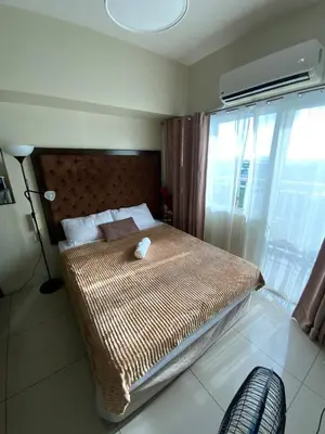 a bedroom with a bed with a large window at Breeze Staycation by Charmed in Sampong