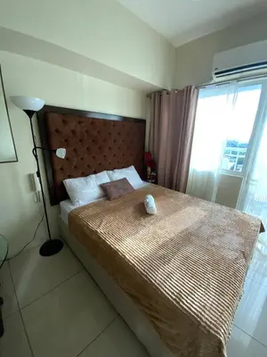 a bedroom with a large bed with a large window at Breeze Staycation by Charmed in Sampong