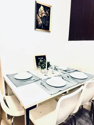 a white dining table with white plates and chairs at High Rise 2br In the Makati Skyline with KTV Pools in Manila