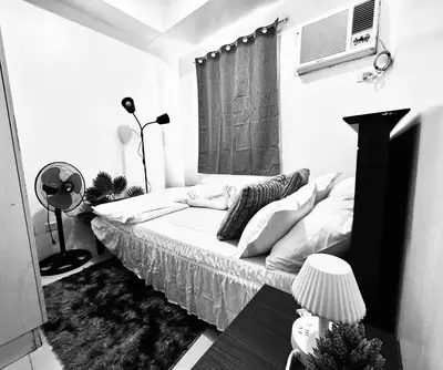 a bedroom with a bed with a fan and a window at High Rise 2br In the Makati Skyline with KTV Pools in Manila