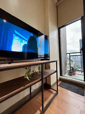 a large flat screen tv in a living room with a window at Condo Living - Pool, Balcony, Gym, Fast WiFi in Manila