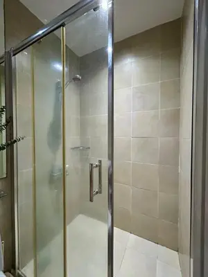 a shower with a glass door in a bathroom at Condo Living - Pool, Balcony, Gym, Fast WiFi in Manila