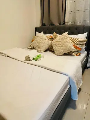 a bed with white sheets and pillows on it at Shore Residences Moa Pasay in Manila