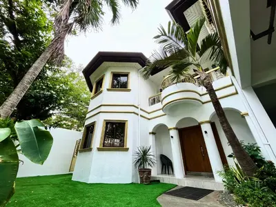 a white house with palm trees in front of it at Elegant 5BR Home Near BGC in Manila