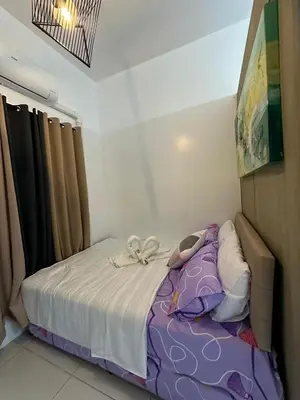 a small bedroom with a bed with purple sheets at Maison dela Mer SMDC Breeze Residences Pasay in Manila