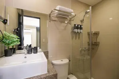a bathroom with a toilet and a sink and a shower at Luxurious Maison at 81 Newport near Terminal 3 Airport in Manila