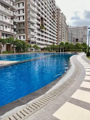 a large blue swimming pool with buildings in the background at Cozy 1BR Staycation at Satori Residences, Pasig in Manila