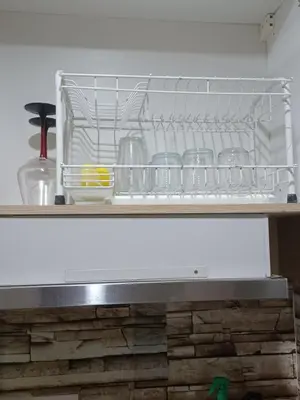 a kitchen counter with a shelf with dishes at Pasay Staycation manila bay view in Manila