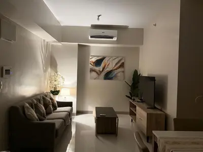 a living room with a couch and a tv at One Uptown Residence, BGC - Standard 2 Bedroom Unit in Manila