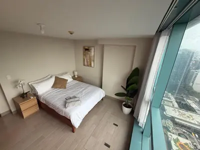 a bedroom with a bed with white sheets and a window at One Uptown Residence, BGC - Standard 2 Bedroom Unit in Manila