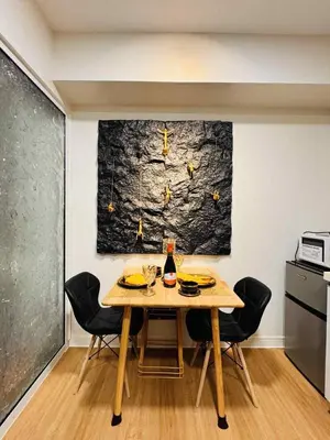 a dining room table with chairs and a bottle of wine at Horiyama staycation azure in Manila