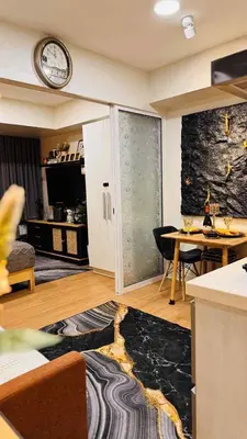 a living room with a table and a clock on the wall at Horiyama staycation azure in Manila