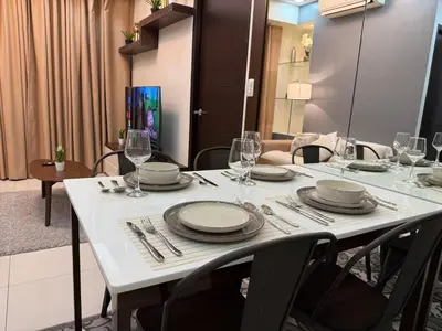 a white table with chairs and plates and wine glasses at Luxury 2BR w Balcony BGC Taguig near Venice Mall in Manila