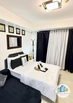 a bedroom with a large white bed with black curtains at Azure Urban Resort Residences by Amóre Suites in Manila