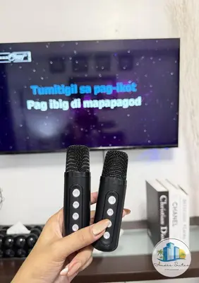 a person holding two microphones in front of a tv at Azure Urban Resort Residences by Amóre Suites in Manila