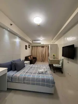 a bedroom with a bed and a living room at Sea Residences Condotel With Balcony, by Rose in Manila