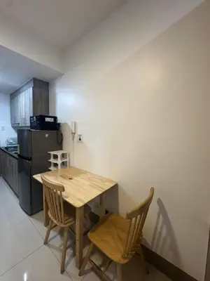 a kitchen with a wooden table and chairs and a refrigerator at FAME RESIDENCES CONDO-TEL Near EDSA Shang in Manila