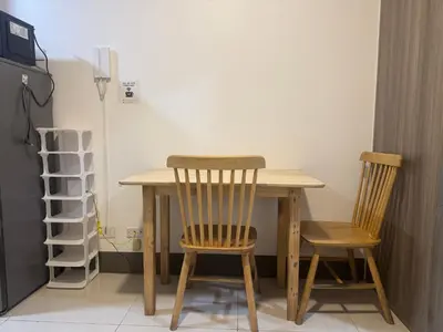 a wooden table with two chairs and a refrigerator at FAME RESIDENCES CONDO-TEL Near EDSA Shang in Manila