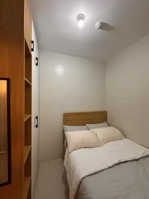 a small bedroom with a bed with white sheets at Eu & El Condo in Manila