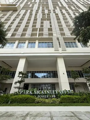 a tall building with a sign in front of it at JUANderful Home at Park McKinley West in Manila